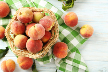 Sweet peach fruit in basket on white wooden table