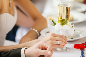 Bride in wedding ring holding glass of champagne in hand.