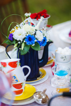 Tea kettle decorated with flowers. Cups on the plates.