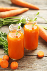 Fresh carrot juice in bottles on a grey wooden table