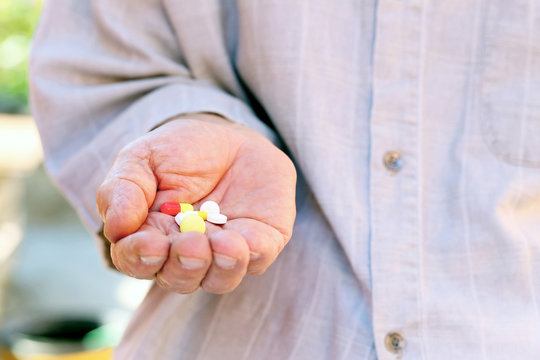 Hand of old senior with pills