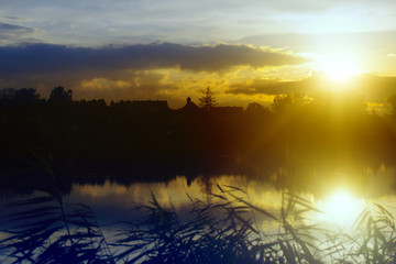 Sunset over the lake, reflection of sun and outline of the village in the background. Skyline of vilage.