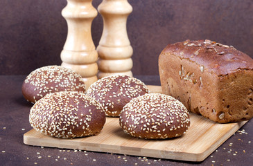 Разный хлеб на разделочной деревянной доске,фон простой.