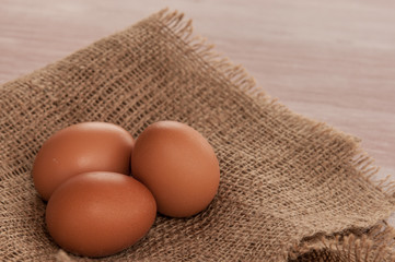 Eggs on burlap over wooden background