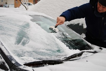 a man removes snow from car - obrazy, fototapety, plakaty