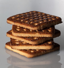 stack of square crackers with pieces and crumbs on slate gray background.