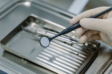 Closeup of dentist hand taking mirror from on of dental tools