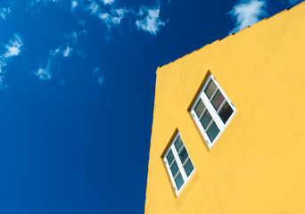 Fototapeta na wymiar gelbe Häuserfassade vor tiefblauem Himmel mit Wolken