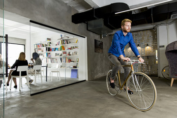 Young man sitting on a bicycle in a modern office