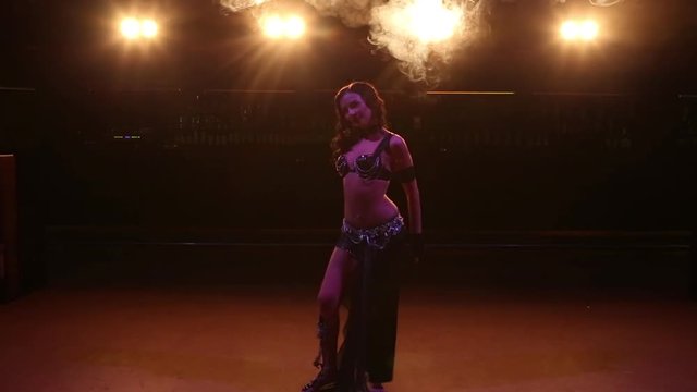 Female dancing belly dance in a nightclub. Smoke background