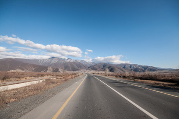 Landscape of asphalt road going off into the mountain passes through the trees, villages and forest places. or rural places of Azerbaijan at sunset