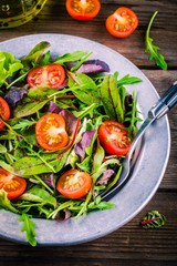 Fresh salad with mixed greens and cherry tomato on wooden background