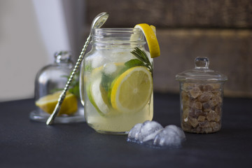 Lemonade with ice in a glass. There are half a lemon behind glass.