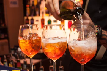 Crédence de cuisine en verre imprimé Cocktail tre cocktail Aperol al bar. Il barista versa champagne in un bicchiere