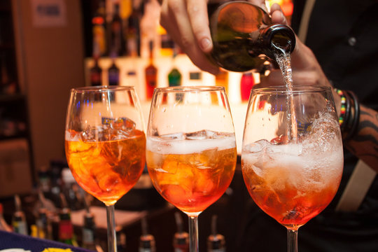 tre cocktail Aperol al bar. Il barista versa champagne in un bicchiere