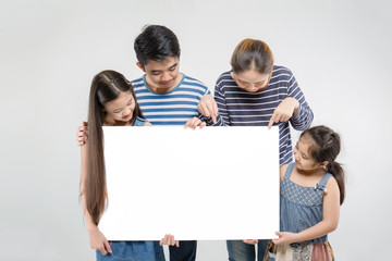 Smiling happy Asian family with big white poster on isolated background
