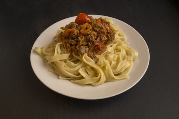 Italian pasta Bolognese in the white plate on black background