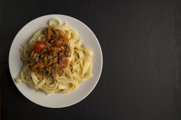 Italian pasta Bolognese in the white plate on black background