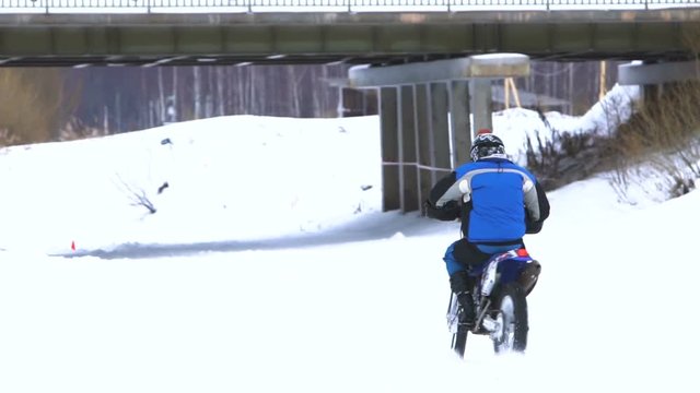 Motorcycle rider on snowy motocross track. Mx rider on snow. Motocross rider on bike, motocross winter season race. Racer motorcycle rides on motocross snowy track in winter. Slow motion.