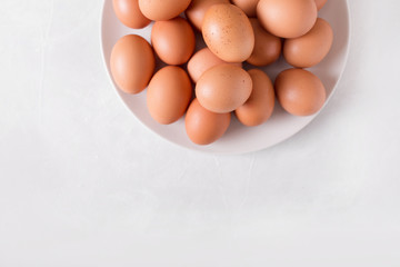 Brown eggs on a white plate on a white background. Eggs.  Easter photo concept. Copyspace