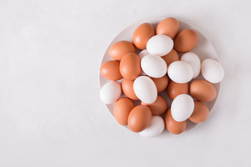 Brown and white eggs on a white plate on a white background. Eggs.  Easter photo concept. Copyspace