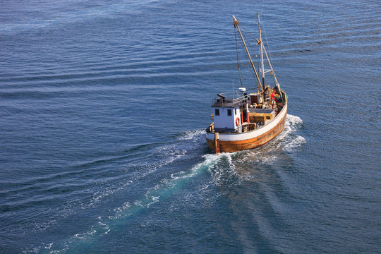 Old wooden fishing boat trawler on sea.