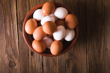 White and brown eggs in a ceramic bowl on a wooden background. Rustic Style. Eggs.  Easter photo concept. Copyspace