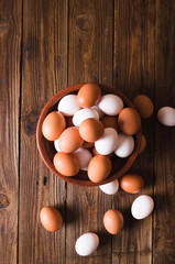 White and brown eggs in a ceramic bowl on a wooden background. Rustic Style. Eggs.  Easter photo concept. Copyspace