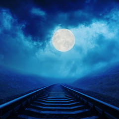 full moon in night clouds over railroad
