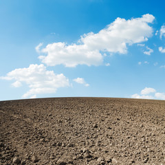 spring plowed field and blue sky with clouds