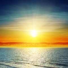 orange sunset in clouds over sea