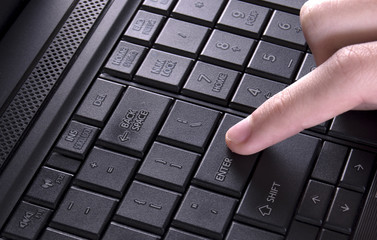 enter key of laptop computer pressed by finger