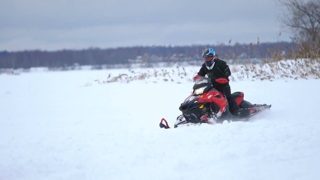 Man driving snowmobile in snowyfield. Snowmobile races. Man on a snowmobile. Winter sports and entertainment. Slow motion.