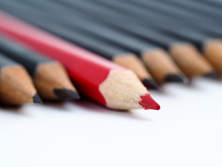 Obraz premium Red pencil standing out from crowd of plenty identical fellows