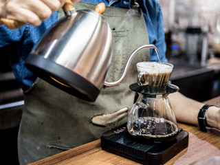 Fototapeta na wymiar Hand drip coffee. Barista pouring water from silver teapot on c
