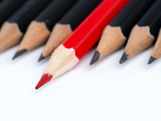 Red pencil standing out from crowd of plenty identical fellows