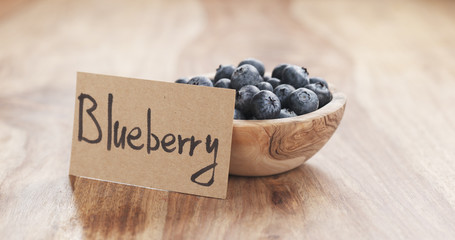 bowl with blueberries with paper card on wood table, 4k photo