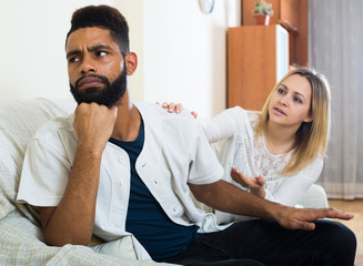 Blonde girl yelling at black boyfriend as quarreling indoors