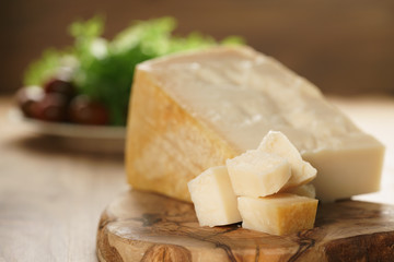 Fototapeta na wymiar hard parmesan cheese cubes on olive cutting board, closeup photo