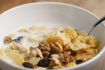 eating corn flakes with fruits and nuts in white bowl, healthy food