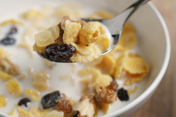 eating corn flakes with fruits and nuts in white bowl, healthy food