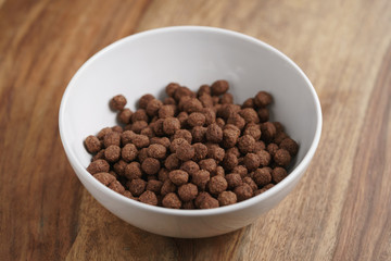 chocolate cereal balls in white bowl for breakfast, shallow focus