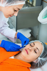 Woman doctor making beauty injection to young female client