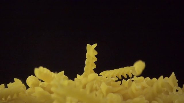Italian fusilli falling. Spirelli pasta on dark background. Slow motion shot