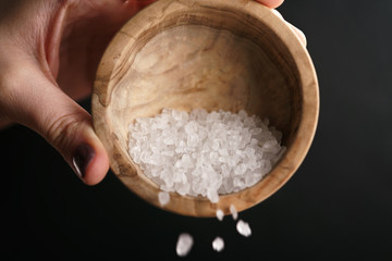 coarse sea salt crystal falling from bowl, closeup photo