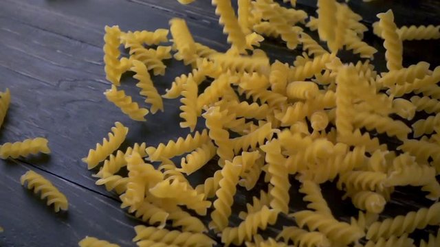 Italian fusilli falling. Spirelli pasta on dark background. Slow motion shot