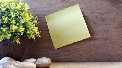 yellow sticky note paper on a wooden table with rock and decorative tree