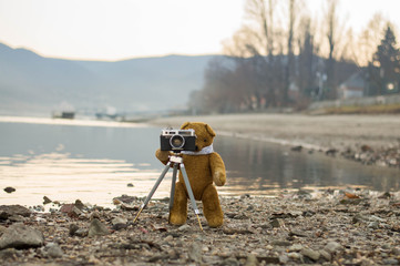 Teddy bear takes photography by the riverside