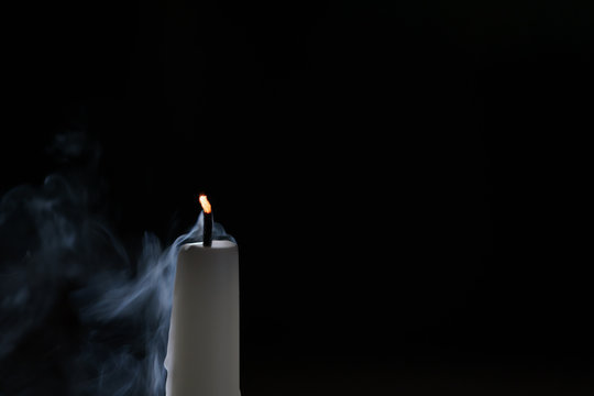 tall candle with smoke trail in the dark environment, shallow focus