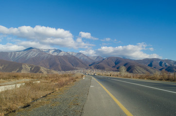 Landscape of asphalt road going off into the mountain passes through the trees, villages and forest places. or rural places of Azerbaijan at sunset